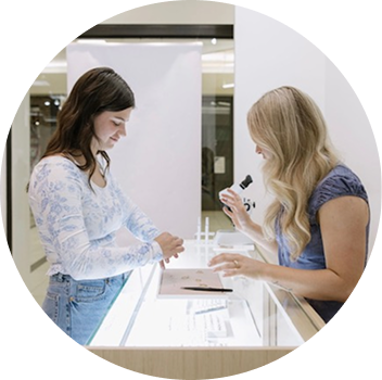 Two women interacting at a counter, one is engaged in conversation while the other is examining items.