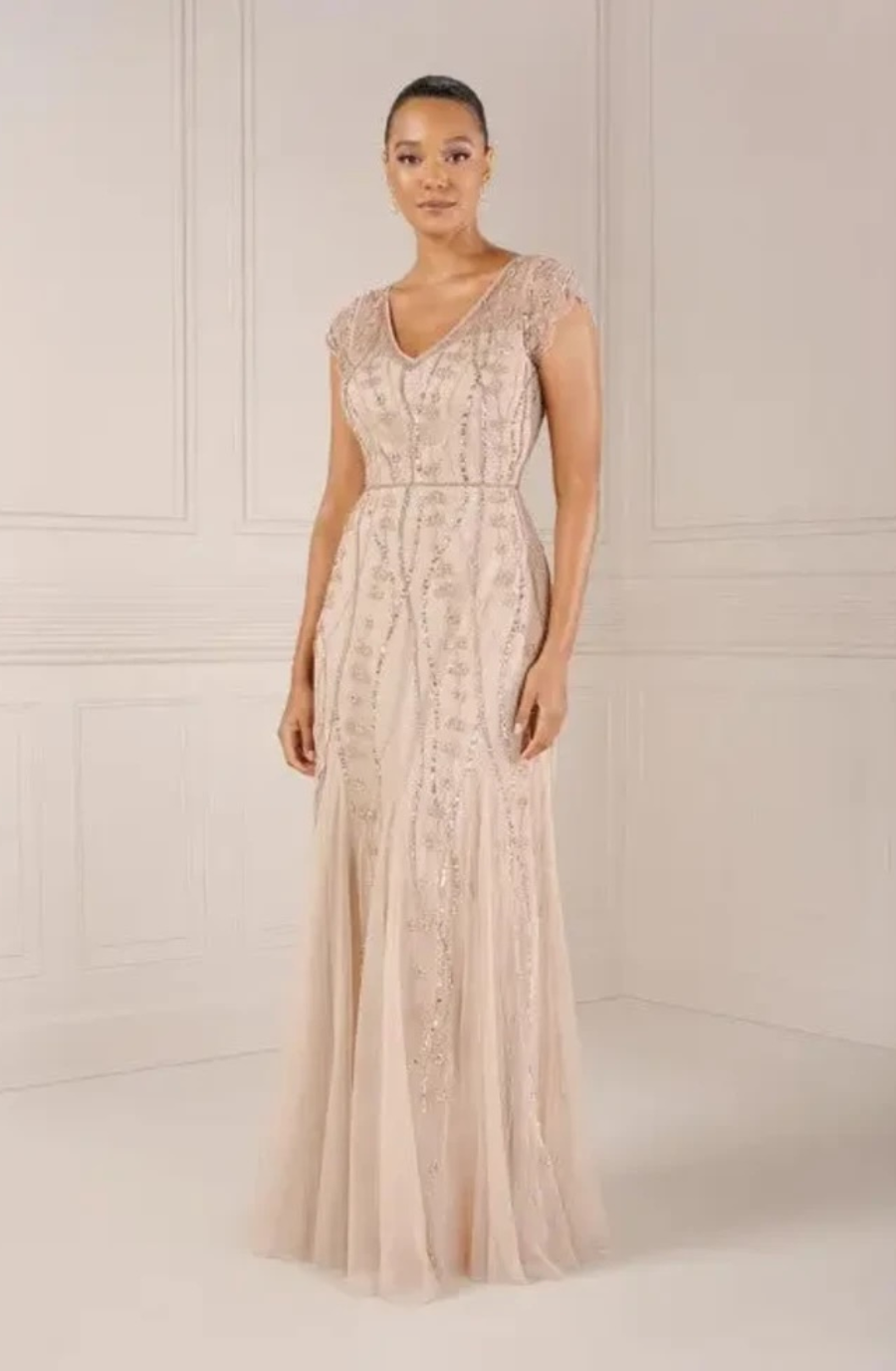 model is wearing a sleeveless beaded evening gown