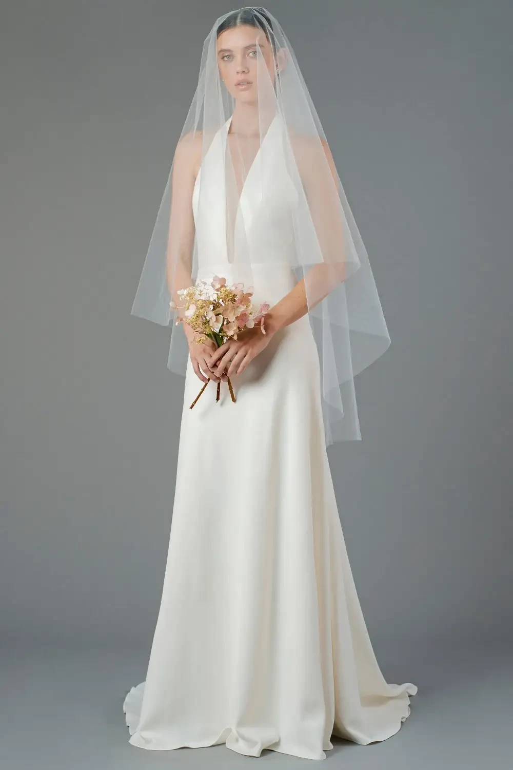 model is wearing a fingertip length veil and gown